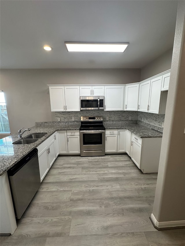 kitchen featuring stone counters, appliances with stainless steel finishes, sink, and white cabinets