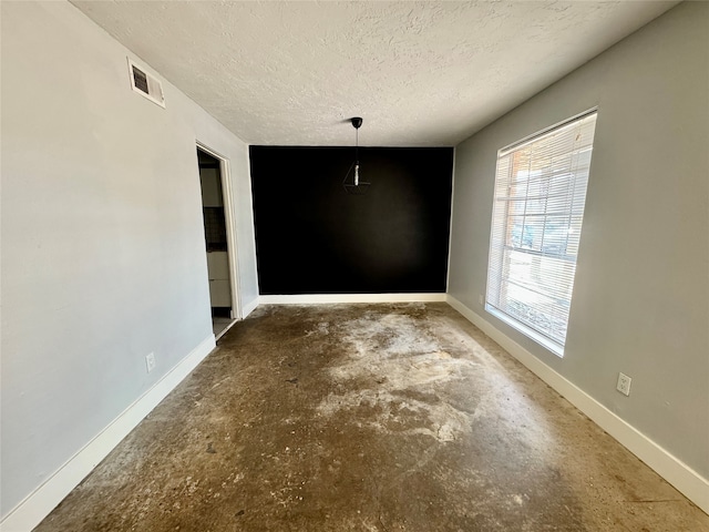 spare room featuring a textured ceiling and concrete floors