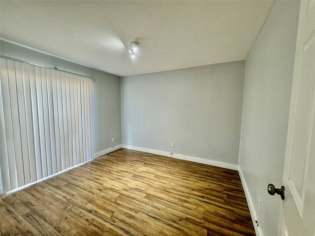 spare room with a textured ceiling and light wood-type flooring