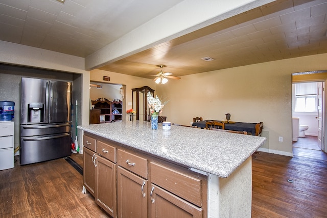 kitchen featuring a center island, stainless steel fridge with ice dispenser, dark hardwood / wood-style flooring, light stone counters, and ceiling fan