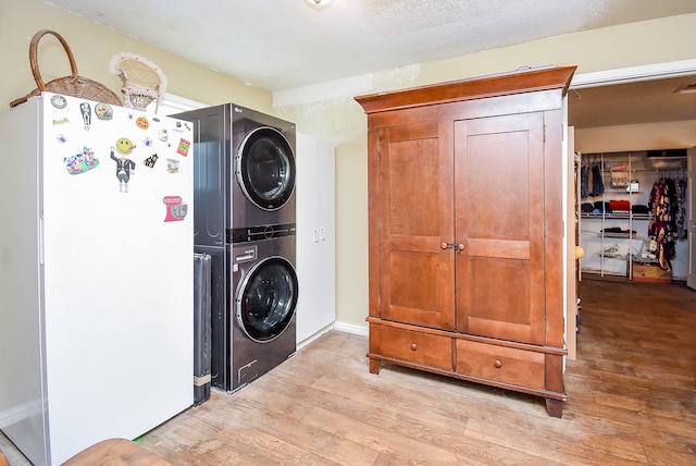 laundry room featuring light hardwood / wood-style floors, a textured ceiling, and stacked washer and clothes dryer