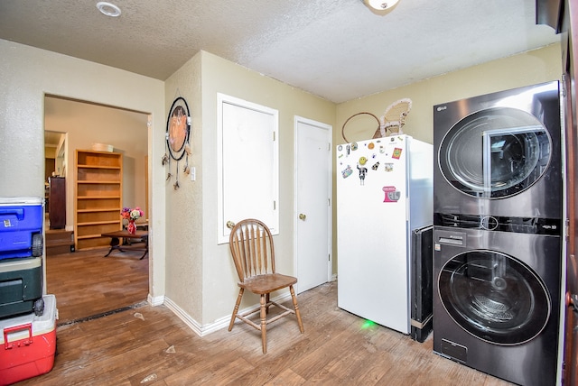 clothes washing area featuring stacked washing maching and dryer, hardwood / wood-style flooring, and a textured ceiling