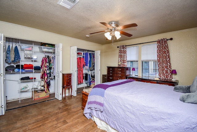 bedroom with a textured ceiling, hardwood / wood-style flooring, and ceiling fan