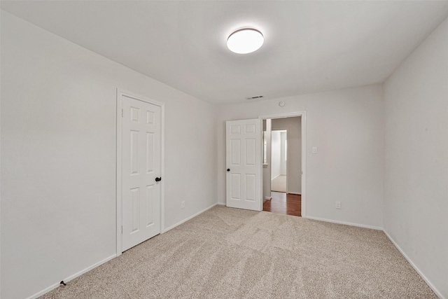 spare room with carpet, visible vents, and baseboards