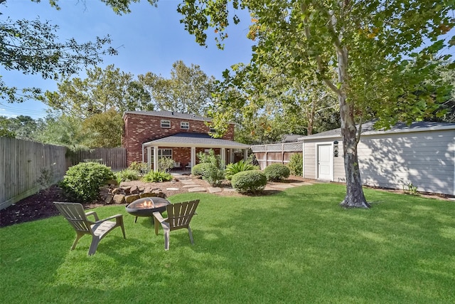 view of yard with an outbuilding, an outdoor fire pit, and a fenced backyard