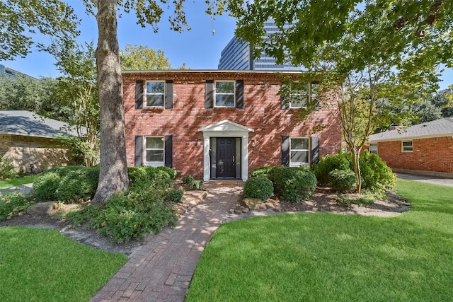 colonial-style house featuring brick siding and a front yard