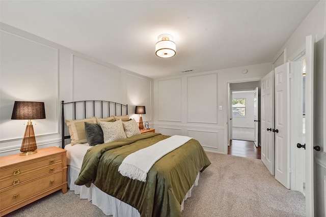 bedroom with carpet floors, visible vents, and a decorative wall