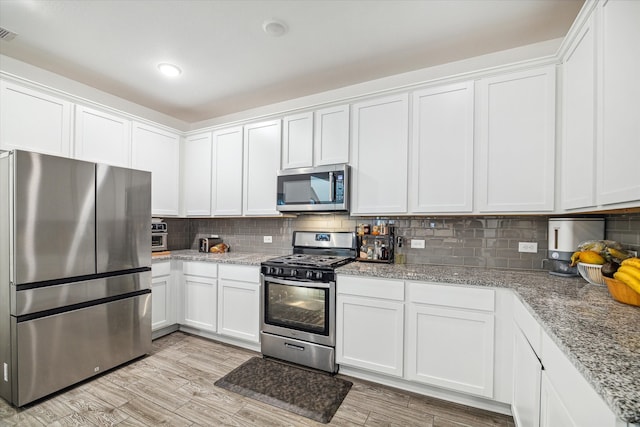 kitchen with stainless steel appliances, light wood-type flooring, backsplash, light stone countertops, and white cabinets