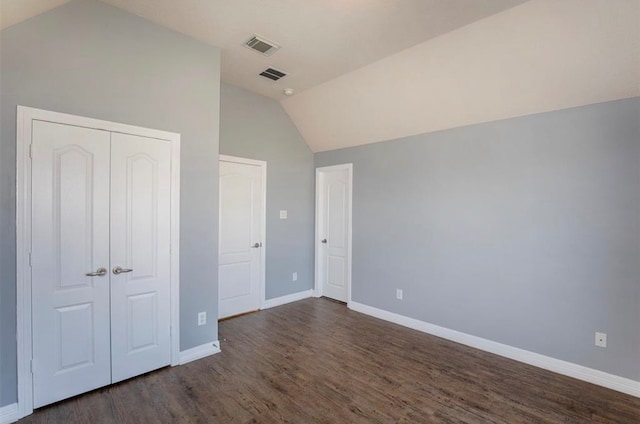 unfurnished bedroom with vaulted ceiling, a closet, and dark hardwood / wood-style flooring