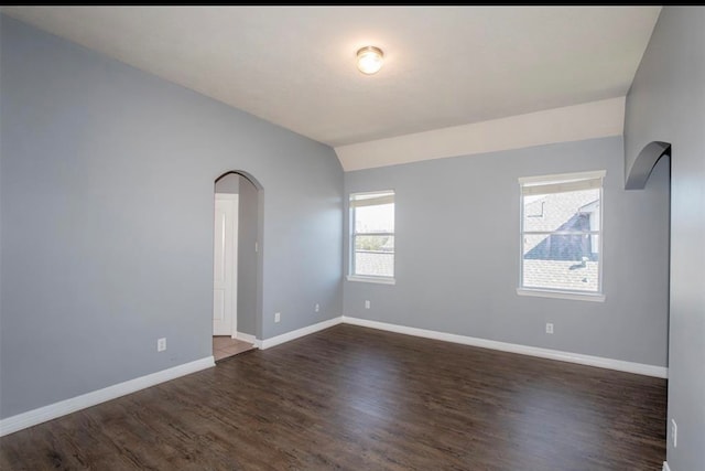 empty room featuring dark wood-type flooring and vaulted ceiling