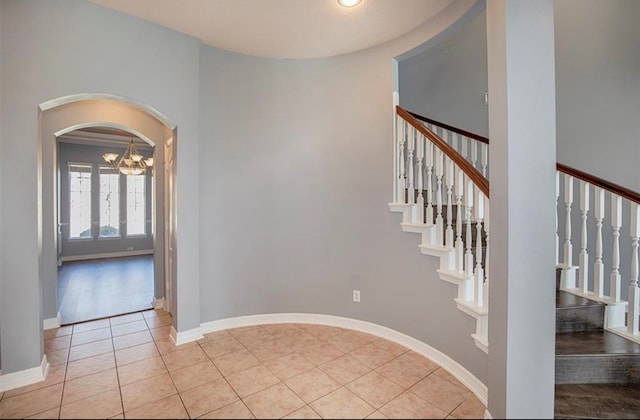 stairway with an inviting chandelier and tile patterned flooring