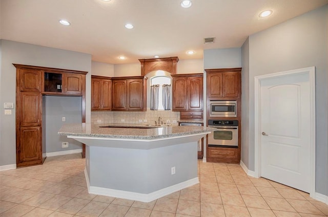 kitchen with decorative backsplash, stainless steel appliances, light tile patterned floors, and a kitchen island