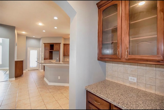 kitchen with decorative backsplash, light tile patterned flooring, and light stone counters