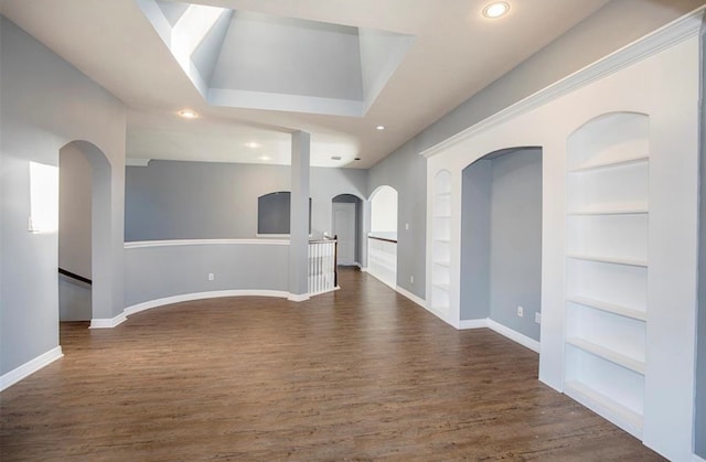 unfurnished living room with dark wood-type flooring and built in shelves