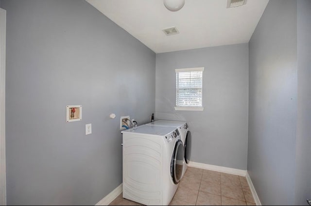 laundry area with washing machine and dryer and light tile patterned floors