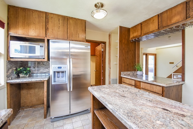 kitchen featuring decorative backsplash, stainless steel fridge, and light stone counters