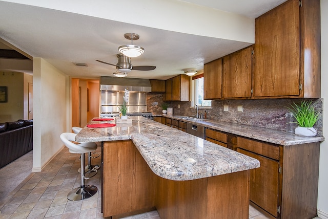 kitchen featuring backsplash, a breakfast bar, ceiling fan, sink, and a center island