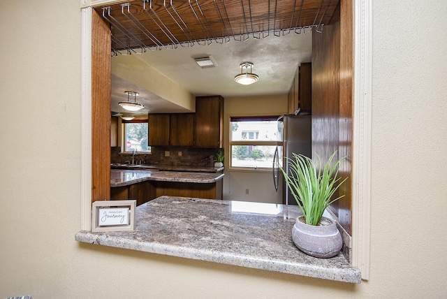 kitchen with tasteful backsplash, stainless steel refrigerator, and sink