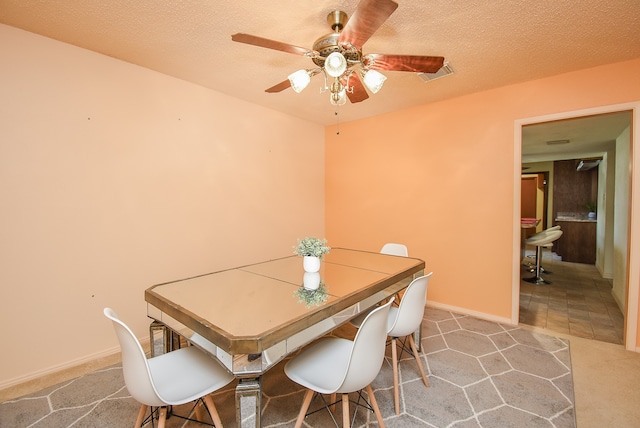 dining room with ceiling fan, carpet, and a textured ceiling