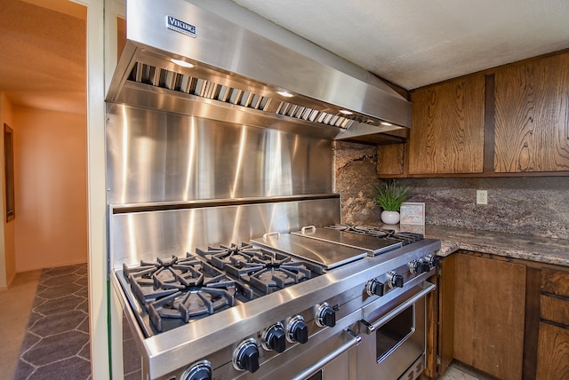 kitchen with tile patterned floors, decorative backsplash, dark stone counters, and stainless steel range