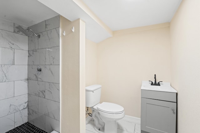 bathroom with toilet, vanity, and tiled shower