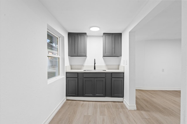 bar featuring light hardwood / wood-style floors and sink