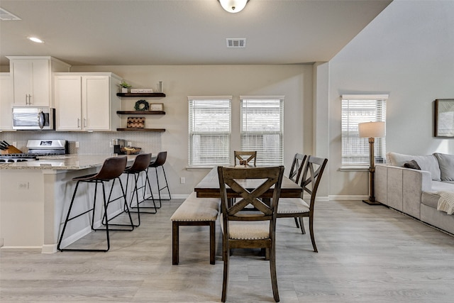 dining area with light hardwood / wood-style flooring and a healthy amount of sunlight