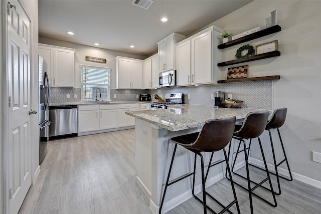 kitchen with a breakfast bar, white cabinets, and stainless steel appliances