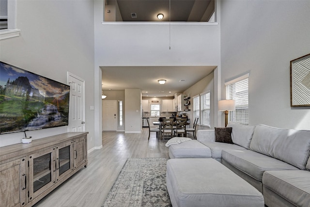 living room with light hardwood / wood-style floors and a towering ceiling