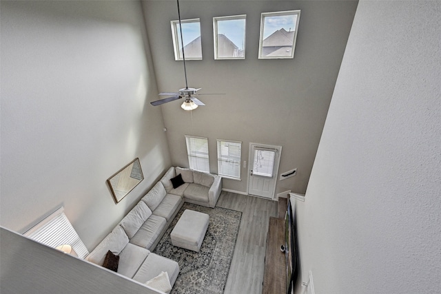 living room featuring a high ceiling, wood-type flooring, a healthy amount of sunlight, and ceiling fan