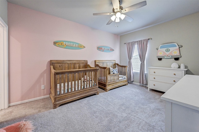 carpeted bedroom featuring a crib and ceiling fan