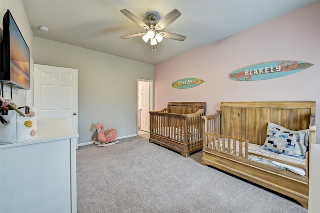 carpeted bedroom with ceiling fan and a nursery area