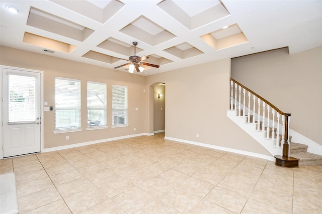 unfurnished living room with beam ceiling, coffered ceiling, light tile patterned floors, and ceiling fan