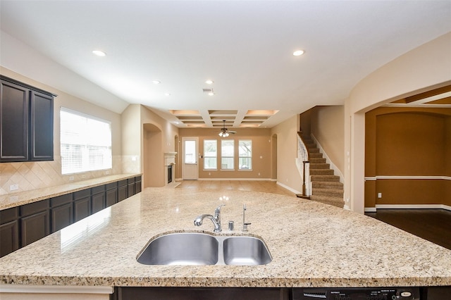 kitchen featuring coffered ceiling, light stone countertops, sink, and backsplash