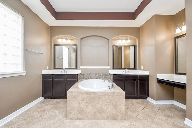 bathroom with vanity, tile patterned floors, tiled bath, and a raised ceiling