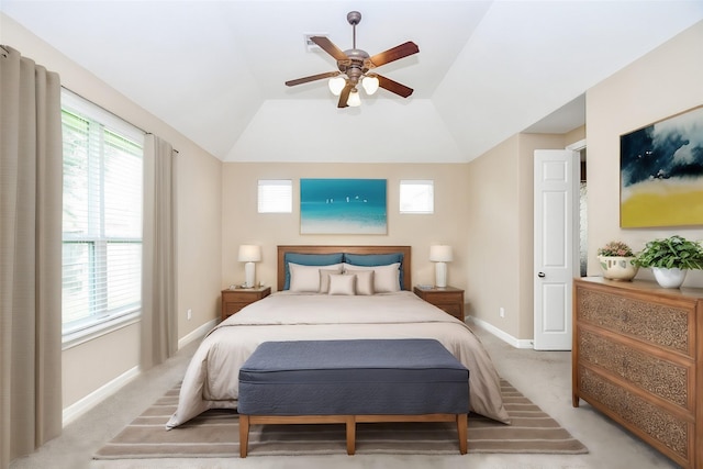 bedroom with light carpet, vaulted ceiling, a raised ceiling, and ceiling fan