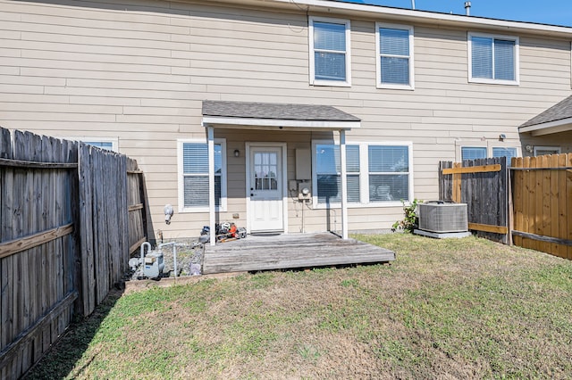 rear view of property with a yard and central AC