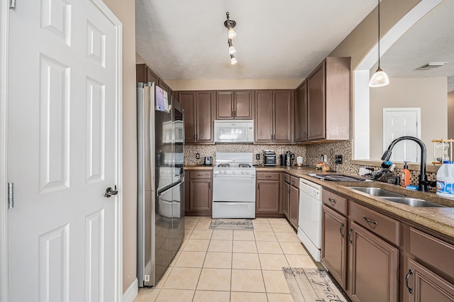 kitchen featuring white appliances, light tile patterned flooring, sink, backsplash, and decorative light fixtures