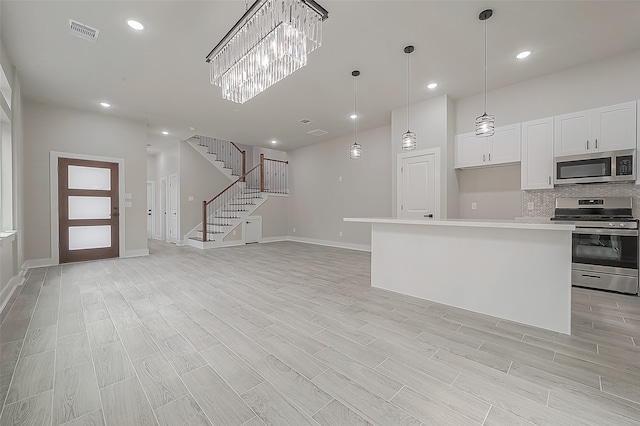 kitchen with tasteful backsplash, a center island, light hardwood / wood-style floors, stainless steel appliances, and white cabinets