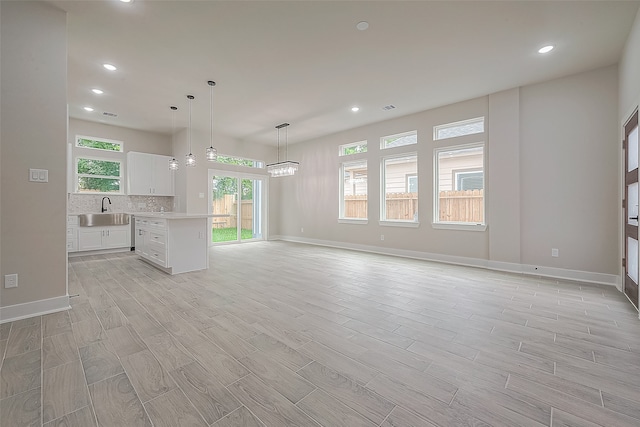 kitchen featuring white cabinetry, light wood-type flooring, sink, decorative light fixtures, and a center island