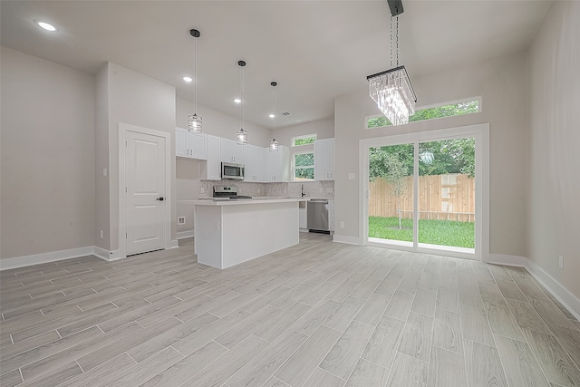 kitchen featuring white cabinetry, stainless steel appliances, a center island, and decorative light fixtures