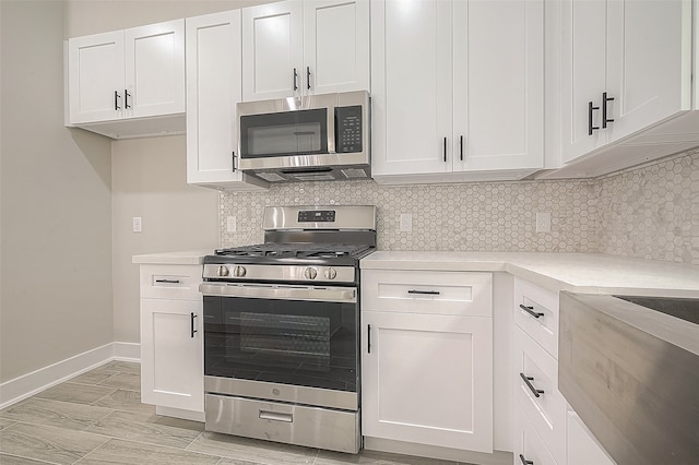 kitchen featuring decorative backsplash, white cabinetry, stainless steel appliances, and light hardwood / wood-style floors