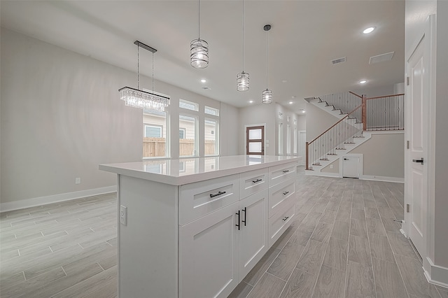 kitchen featuring a wealth of natural light, a kitchen island, light hardwood / wood-style flooring, and hanging light fixtures