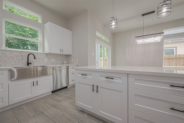 kitchen with white cabinetry, a healthy amount of sunlight, stainless steel dishwasher, and hanging light fixtures