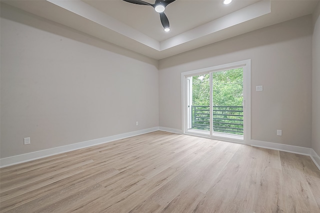 unfurnished room with light hardwood / wood-style floors, a tray ceiling, and ceiling fan