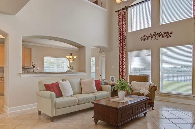 tiled living room with ornamental molding, a towering ceiling, a notable chandelier, and a healthy amount of sunlight