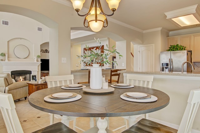 tiled dining space with ornamental molding, a notable chandelier, and sink