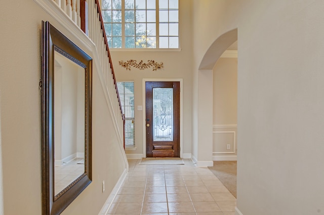 tiled entryway featuring a high ceiling and crown molding