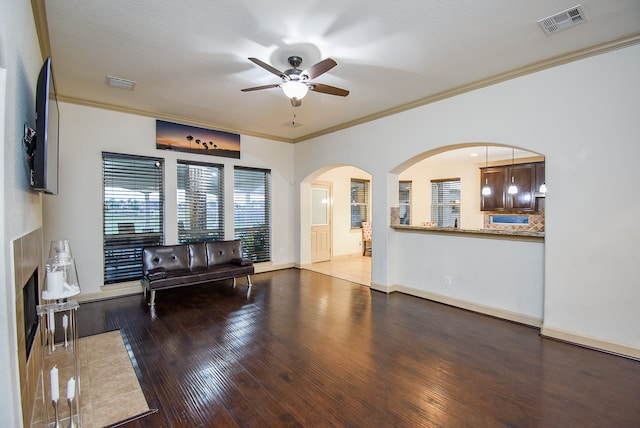 living room with ceiling fan, ornamental molding, a textured ceiling, and dark hardwood / wood-style floors