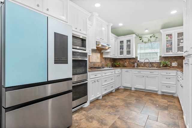 631 Apache St, Houston, TX 77022 - kitchen with stainless steel appliances, a sink, white cabinetry, dark stone finish flooring, and decorative backsplash